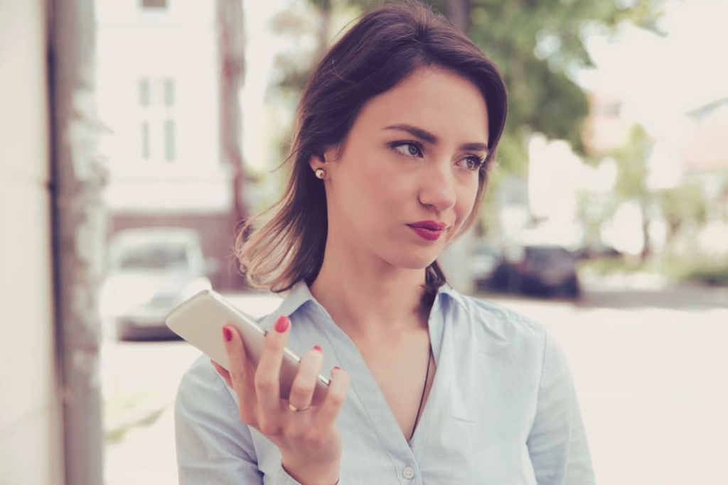 Woman with a smirk and holding a phone.