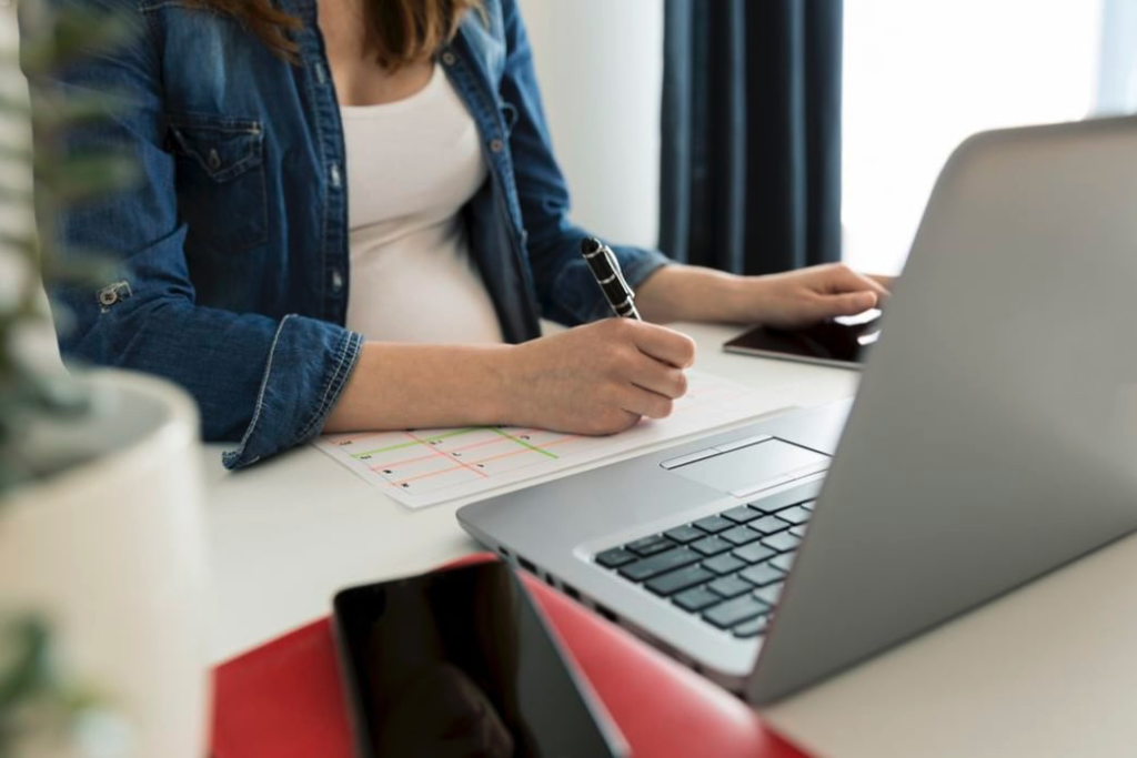 Woman with calendar and computer in front of her on a table. 