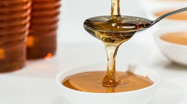 Honey drizzled onto a spoon and into a small bowl.  
