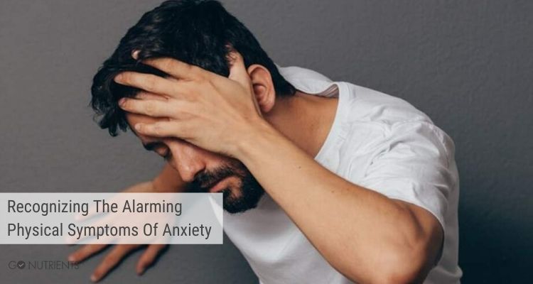Man leaning on a wall and holding his head.   Physical symptoms of anxiety may include headaches