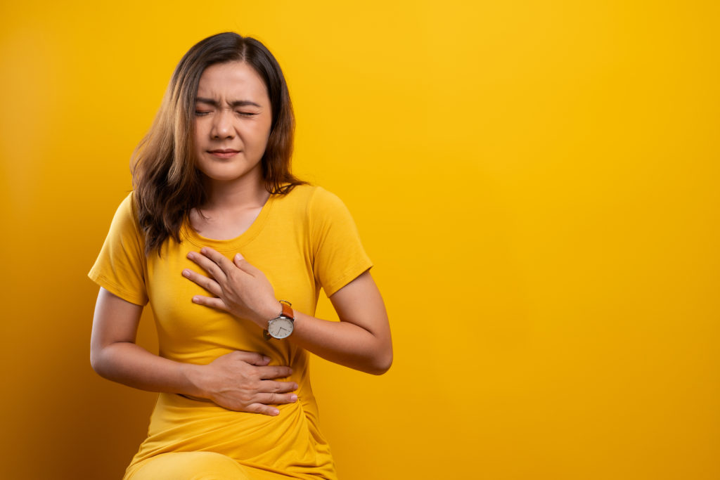 Woman has stomachache isolated over yellow background