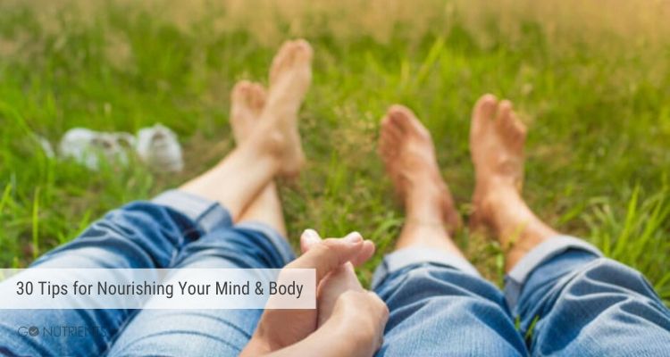 A couple holding hands and barefooted relaxing in a field.  Taking time out for their mind and body.