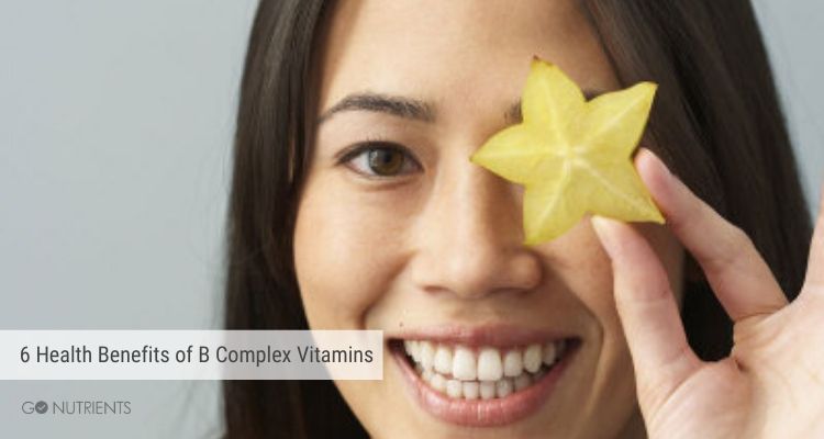 A brunette woman with a star fruit in from of her face. 