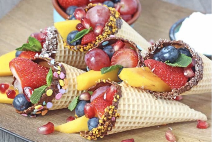 Chocolate dipped waffle cones with fruit inside. 