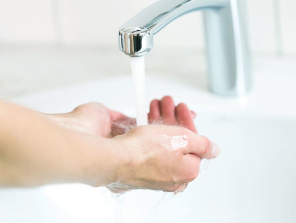 Female hands with suds and held under running water.  Hand washing example 
