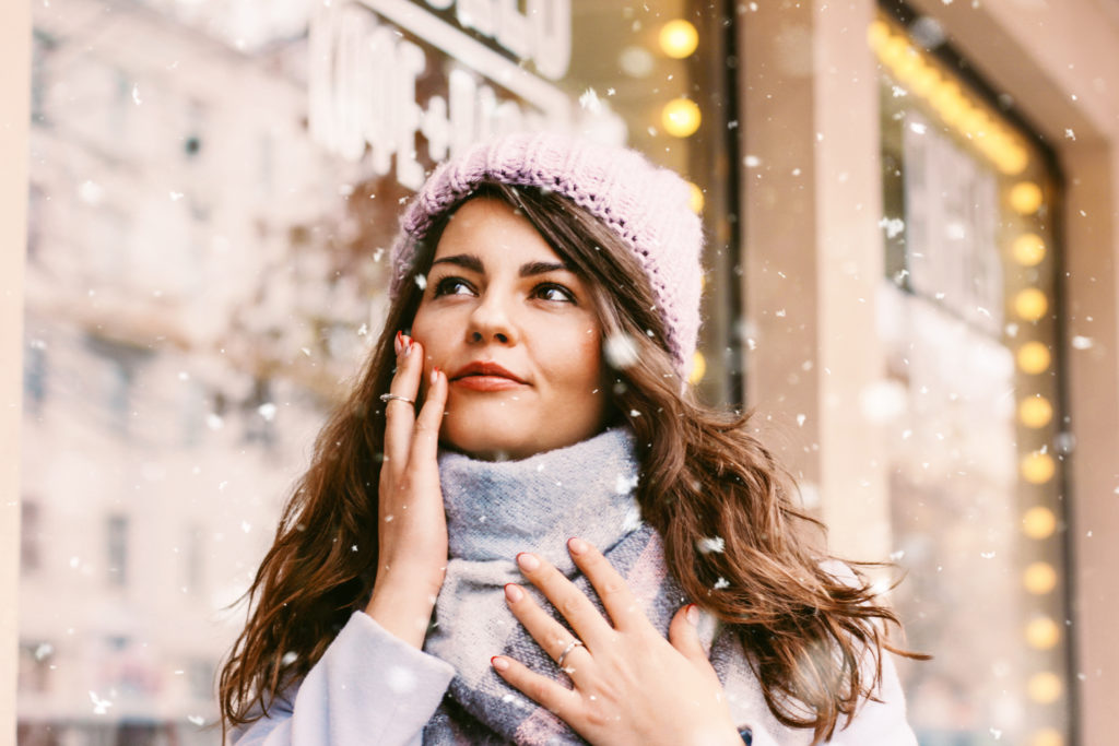 Portrait of young beautiful woman in coat and hat enjoing the first snow