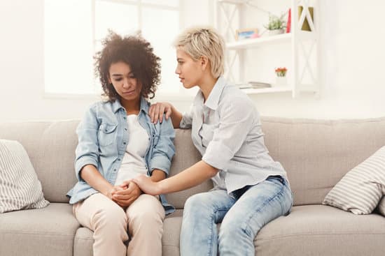 One woman talking with another on a couch. Helping a friend with depression or SAD.