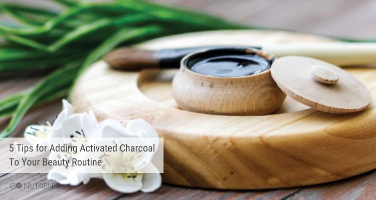 Adding activated charcoal - Image of activated charcoal in wood container with foliage in background.