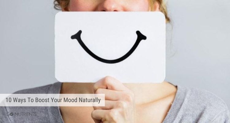A woman holding a white card with a smile drawn on it.  10 Ways to boost your mood naturally