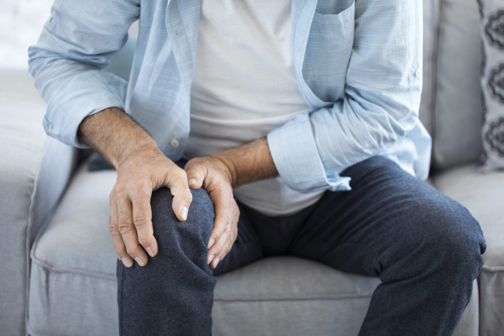Man holding his knee and suffering from arthritis pain.
