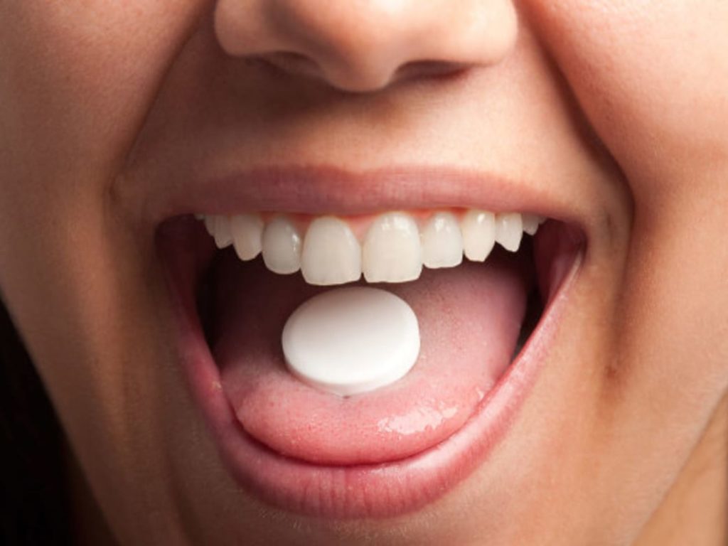 A mouth with a zinc lozenge on the tongue. 