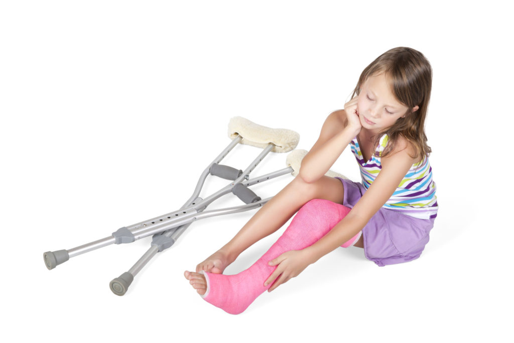 First grader with a cast on her left leg and crutches next to her. 