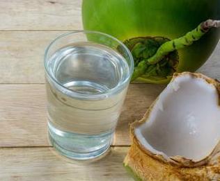 Glass of coconut water with a sliced coconut next to it. 
