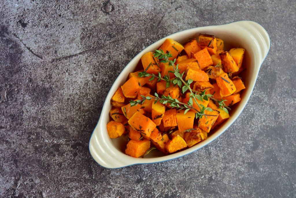 Roasted cubed pumpkin with thyme on grey background