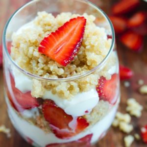 Glass tumbler with strawberries, quinoa, and greek yogurt layers. 