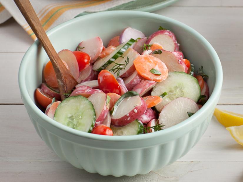 Spring Garden Potato Salad in a bowl with a wooden spoon.