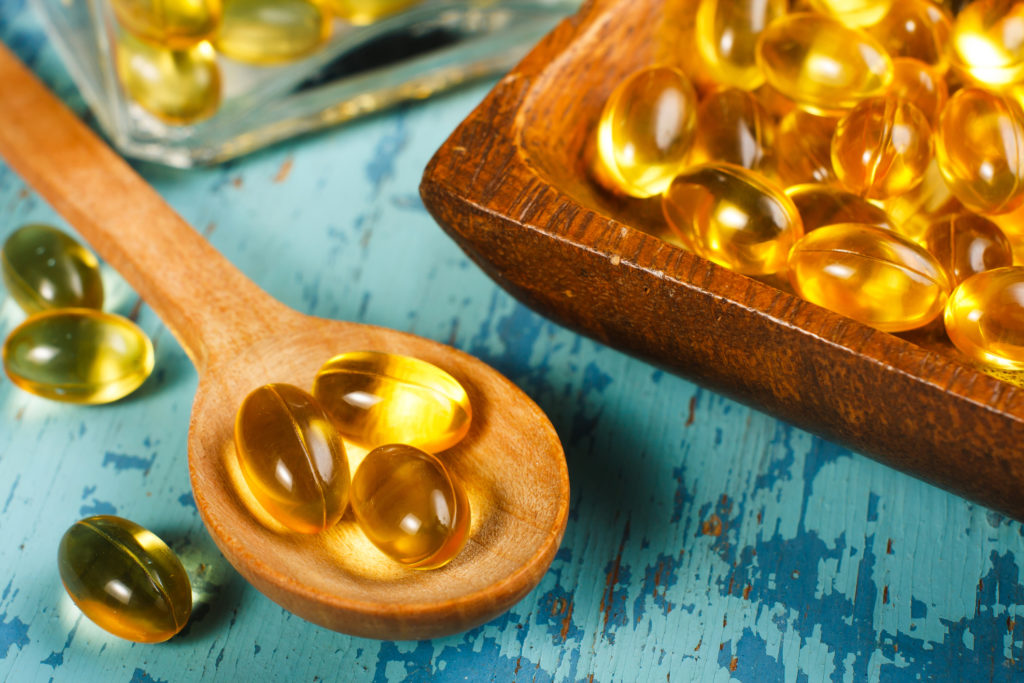 Fish Liver Oil Capsules on wooden spoon
