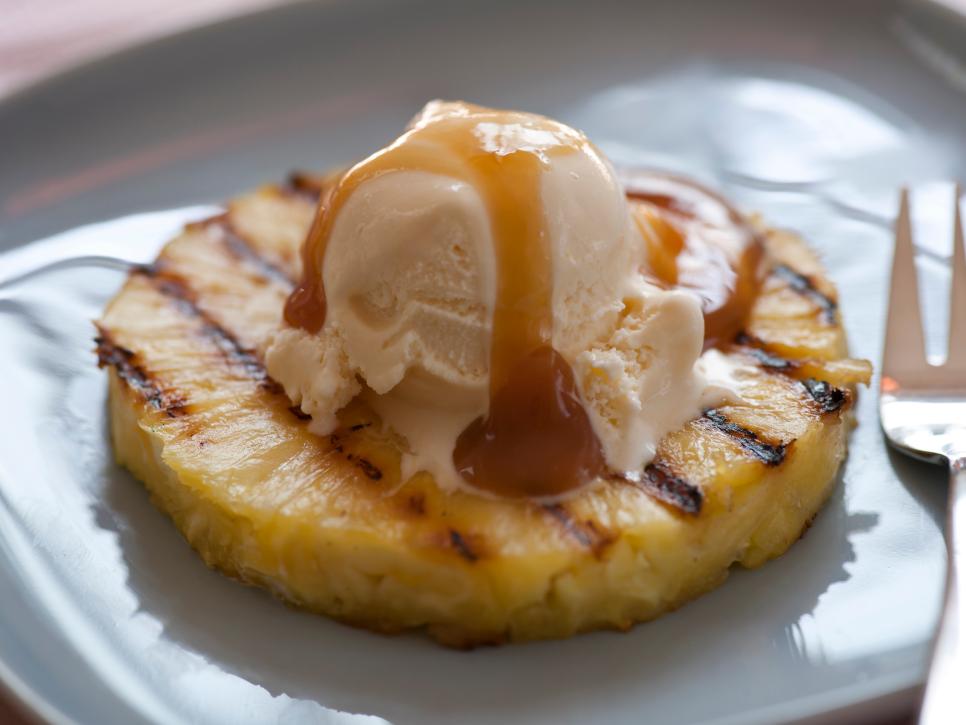 Grilled Pineapple with Vanilla Ice Cream and Rum Sauce plated with a fork 
