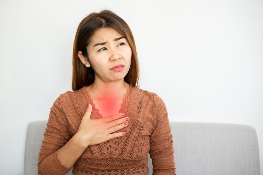 Asian woman suffering from gastroesophageal, acid reflux disease or heartburn