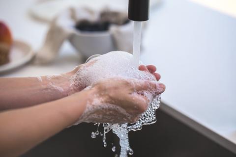 person washing hands with suds and under running water