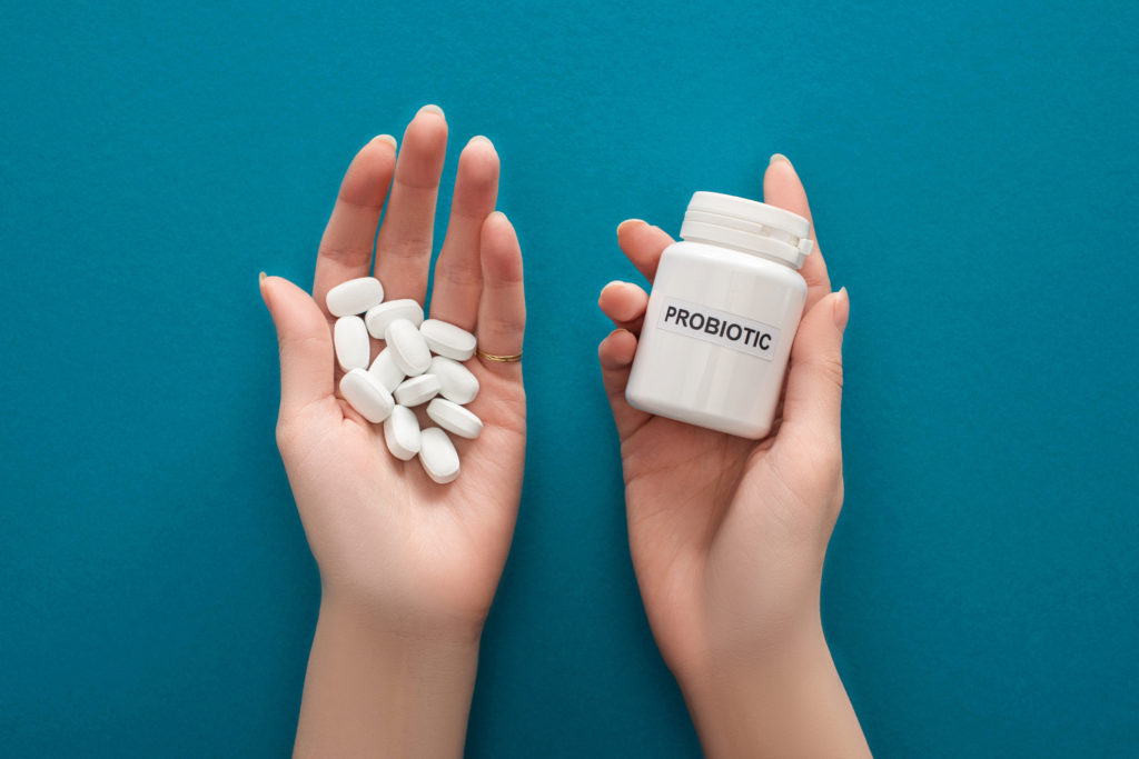 probiotic pills in one hand and the bottle in the other hand