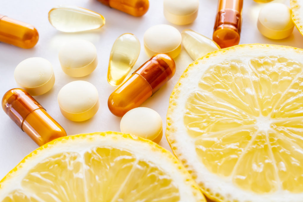 Vitamin C capsules and pills with slices of oranges. 