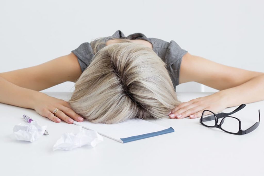 image provided by Oxygen Magazine --
Woman with gray hair, head on a desk and crumpled papers around her with her glasses. 