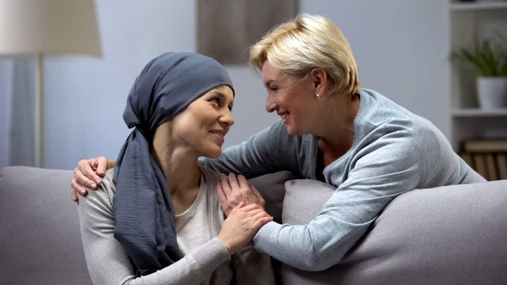 Mom supporting and hugging her daughter with cancer, visits in oncohospital