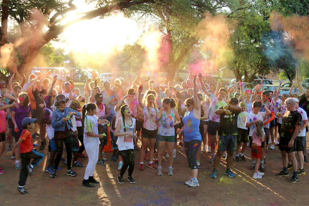 Rustenburg Marathon Club Rainbow Run. Crowd of runners throwing powder paint into air at start of colour run.