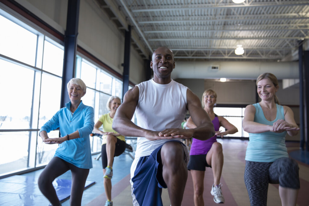 Personal trainer leading exercise class with mature women in gym