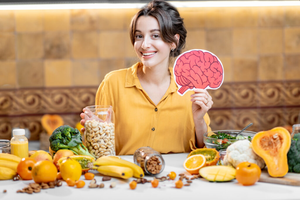 Woman holding human brain model with variety of healthy fresh food on the table.