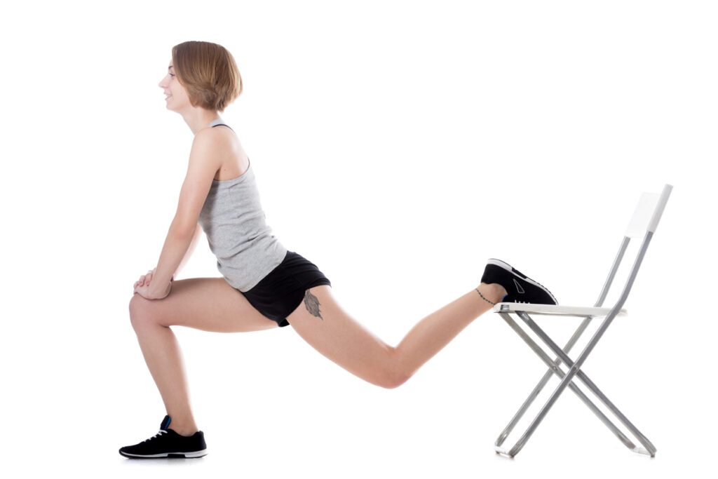 Young cheerful sporty attractive woman doing fitness training, exercises for hips and buttocks with office chair, full length isolated studio image on white background